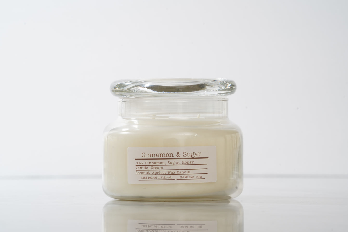 Jar candle labeled 'Cinnamon & Sugar' on a white background